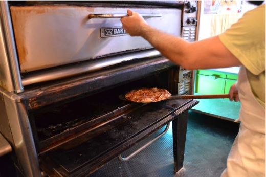 A cook puts a new pizza into the oven at Pizza house on Commercial Street in Springfield, Mo.